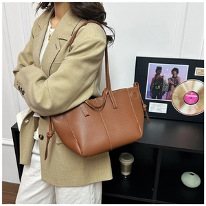 Detail of brown leather tote bag showing white contrast stitching and side drawstring