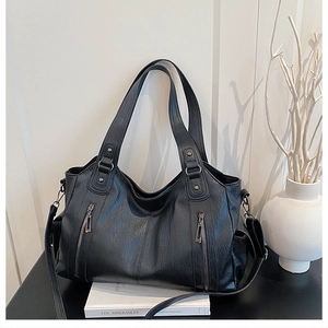 Black leather tote bag with dual zippers and adjustable strap for shoulder or crossbody wear