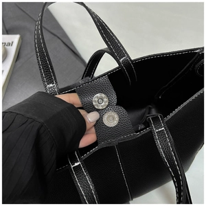 Detailed view of the black pebbled tote bag with magnetic closure and contrast stitching