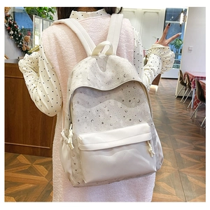 Detailed view of cream backpack with celestial prints and woven zipper pulls on model