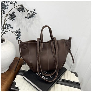 Dark brown lychee leather tote bag with white stitching on a stylish lifestyle background