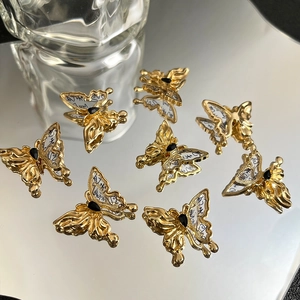 Makro-Detail von goldenen Schmetterlingsanhängern mit schwarzen Edelsteinen und Tinte
