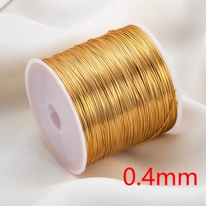 Macro detail of 0.4mm golden copper wire for jewelry making on white fabric backdrop