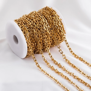 Macro detail of gold-plated stainless steel square link chain on a white spool