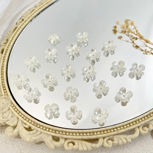 Macro-opname van witte bloemvormige parels voor DIY-sieraden maken op een spiegel