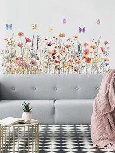 Stickers muraux fleurs sauvages et papillons décorant le salon au-dessus d'un canapé gris