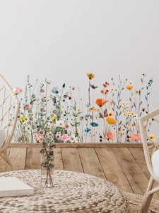 Détail de stickers muraux fleurs sauvages colorées sur un mur blanc au-dessus du parquet