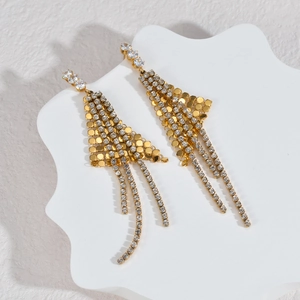 Elegante goudkleurige kwastjesoorbellen met fonkelende strass op een witte steenplaat