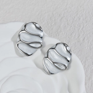 Minimalist silver oval earrings with white wavy enamel inlay on a textured base