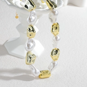 Close-up of baroque style necklace with white faux pearls and irregular gold beads