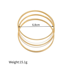 Detail van drie gouden geometrische armbanden met 6,8 cm diameter en reliëftextuur
