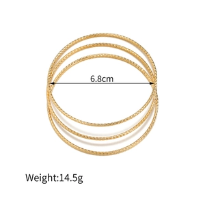 Detail van gouden geometrische armbanden met diamantgeslepen textuur en 6,8 cm diameter