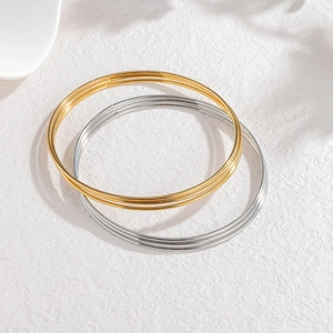 Detail van minimalistische goud- en zilverkleurige armbanden op een witte steen