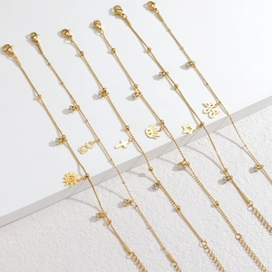 Detail of gold stainless steel bracelets with charms like sun and zircon on white steps
