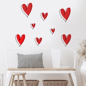 Detail of red heart wall decals with black hand-drawn outlines on a white bedroom wall