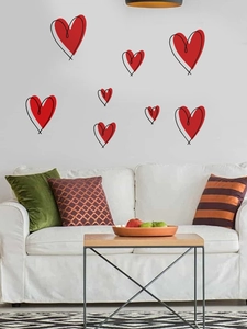 Detail view of red heart wall decals arranged over a white sofa in a living room decor