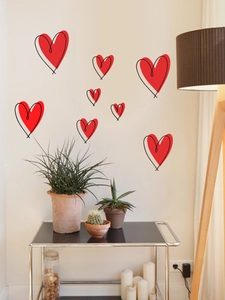 Red hand-drawn heart wall stickers displayed in a cozy living room scene on light walls
