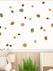 Neutral tones polka dot wall stickers on white wall above wood paneling in nursery