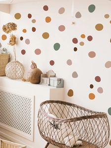 Detail of matte irregular polka dot wall decals in earthy tones on a cream modern wall