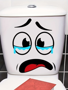 Detail of funny crying cartoon face toilet sticker on white ceramic surface