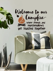 Detail of campfire wall decal with English phrases above a minimalist green sofa