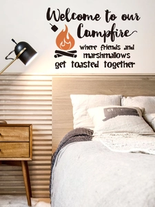 Detail of campfire wall decal with typography above bed in a cozy bedroom setting