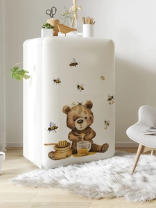 Detailed view of hand-drawn cartoon bear and honey bee wall stickers on a retro fridge
