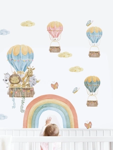 Detail of watercolor animal hot air balloon wall decals in a warm nursery room setting