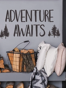 Detail view of Adventure Awaits wall sticker with pine tree art in a cozy interior setting