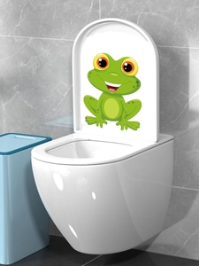 Detail showing a cute green cartoon frog sticker applied on a white modern toilet lid