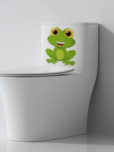 Detail of cute green frog toilet sticker on a white ceramic tank in a modern bathroom