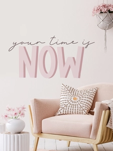 Dettaglio dell'adesivo murale 'your time is NOW' sopra una poltrona rosa in arredo moderno