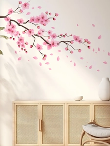 Primo piano di adesivi murali con rami di pesco rosa e petali realistici su muro bianco