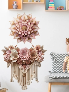 Dettaglio decorazione murale con fiori rosa e frange boho su una parete bianca