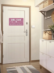 Gros plan du panneau rose Girl Cave avec texte No Boys Allowed sur une porte blanche