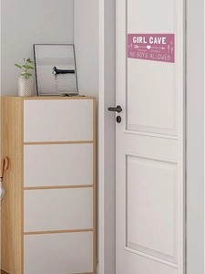 Plaque de porte rose Girl Cave accrochée à une porte blanche dans une chambre