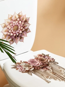 Dettaglio di adesivi floreali 3D rosa e champagne con nappe su un coperchio del WC in ceramica