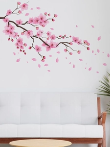 Adesivo murale con ramo di fiori di ciliegio rosa sopra un divano bianco moderno