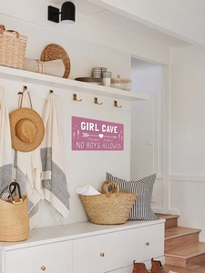 Détail d'une plaque murale Girl Cave rose avec texte blanc sur un mur minimaliste