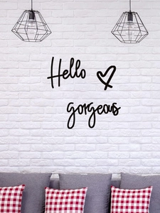 Detailed close-up of Hello Gorgeous wall decal on a white brick wall in a modern living room