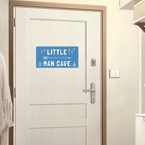 Sticker Little Man Cave bleu sur porte blanche avec motifs de forêt et de tente