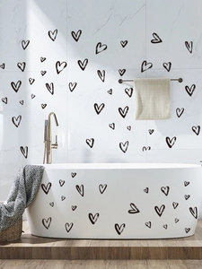 Detail of self-adhesive black heart wall stickers applied on white bathroom tiles