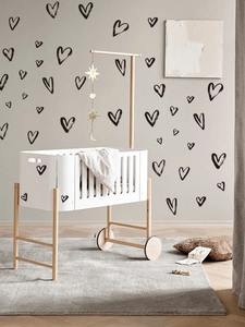 Detail of hand-drawn black heart wall decals on warm grey wall in a cozy nursery room