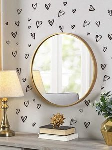 Detail showing black heart wall decals next to a round gold mirror in a modern room