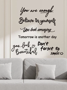 Détail de l'autocollant mural PVC avec phrases inspirantes au-dessus du canapé gris