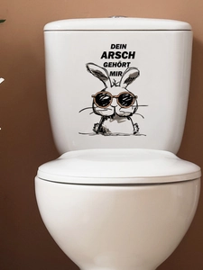 Close-up of funny cartoon rabbit toilet sticker with German text on white ceramic surface