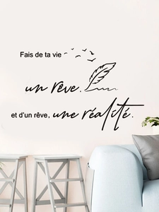 Detail of French quote wall decal with birds and feathers above a modern blue sofa