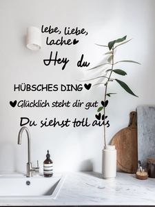 Detail of minimalist black German wall decals with inspirational text in a modern kitchen
