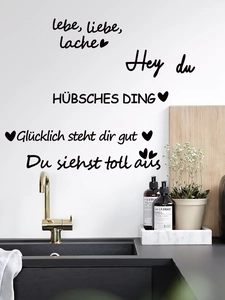 Detailed close-up of German inspirational vinyl wall stickers on a modern kitchen wall