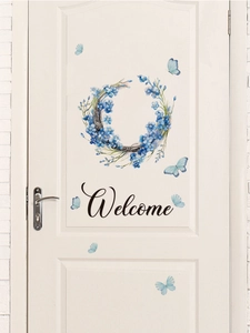 Dettaglio ghirlanda di miosotide blu con farfalle e testo Welcome su una porta bianca